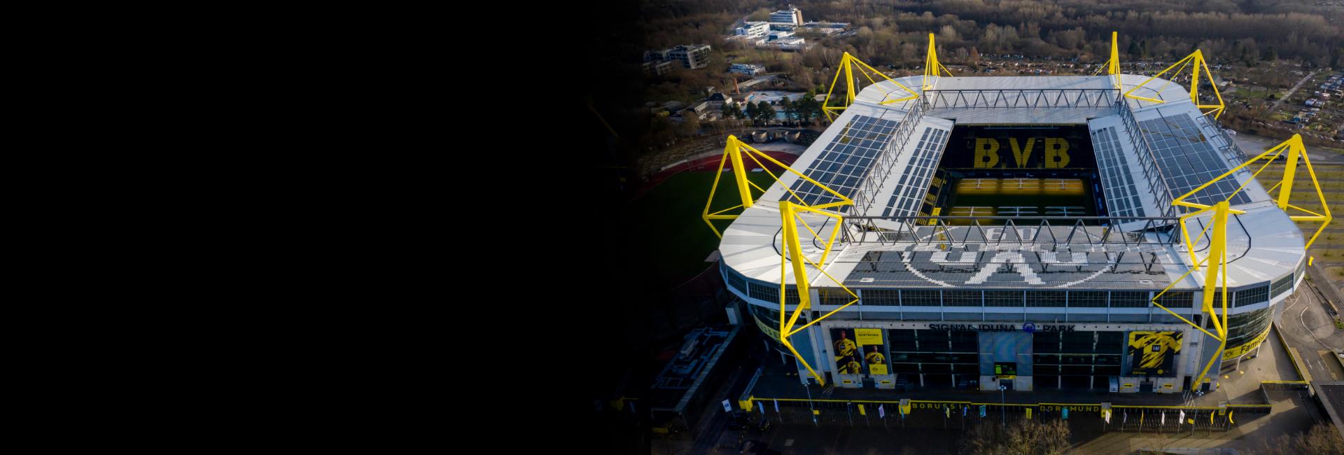 Matchday Experience: Wie Produktdaten ganz vorne mitspielen Feature Luftaufnahme des Signal Iduna Parks, dem Stadion von Borussia Dortmund, mit den markanten gelben Pylonen und dem "BVB" auf den Sitzen; das Stadion ist von einem Waldgebiet und Parkplätzen umgeben.