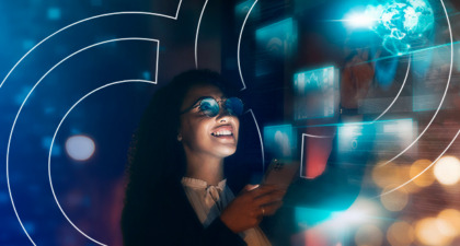 Woman interacting with a futuristic digital interface displaying holographic screens and a glowing globe, holding a smartphone, and smiling
