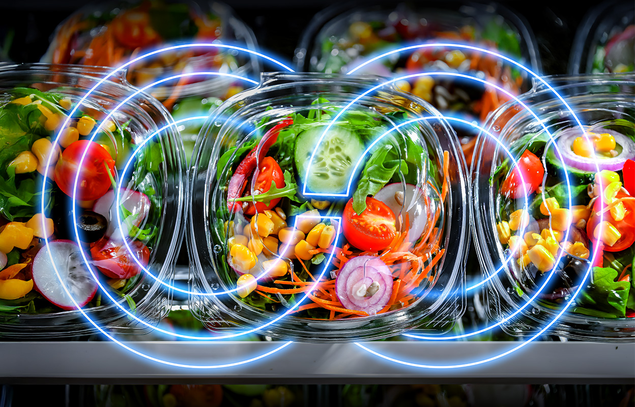 Plastic containers filled with fresh salads—lettuce, tomatoes, cucumber, corn, carrots, radishes, olives, and red onions—are displayed on grocery shelves with blue circular digital effects layered over them.